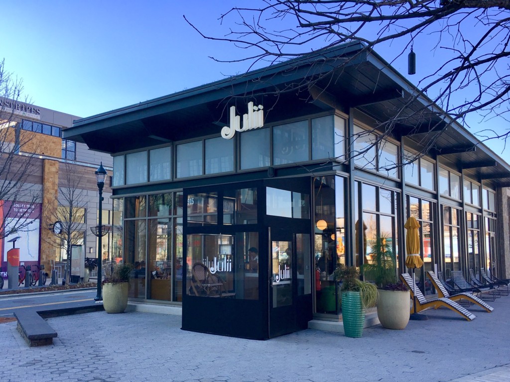 An exterior view of Julii, an intimate restaurant located in the Pike and Rose development, that stands out architecturally for its use of eye-catching floor to ceiling windows.