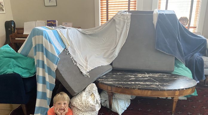 This photo shows how children propped cushions on a sofa and draped towels over them to make a tent in their living room.