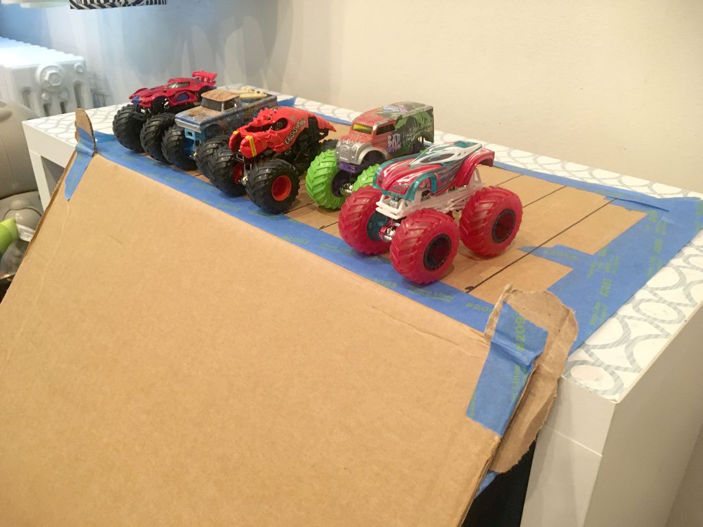 Monster trucks line up for a race on a cardboard racetrack!