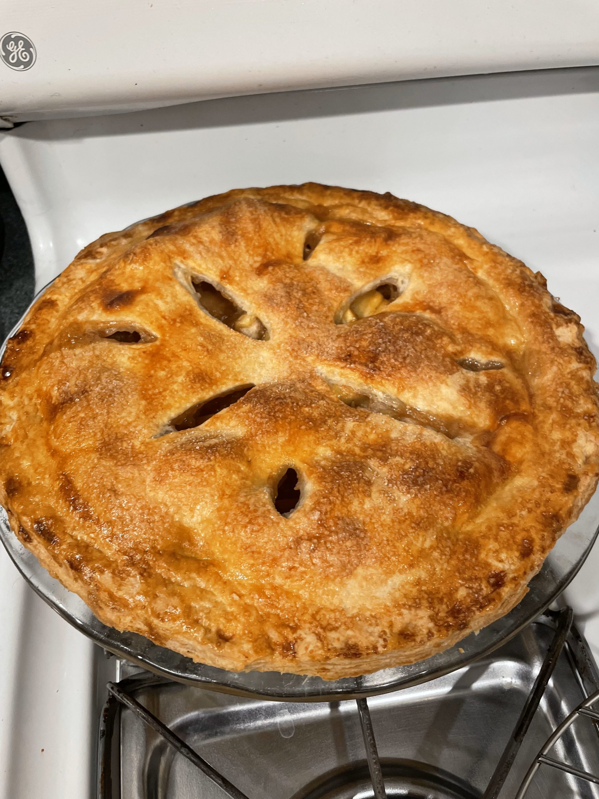 A baked apple pie sitting on a white stove
