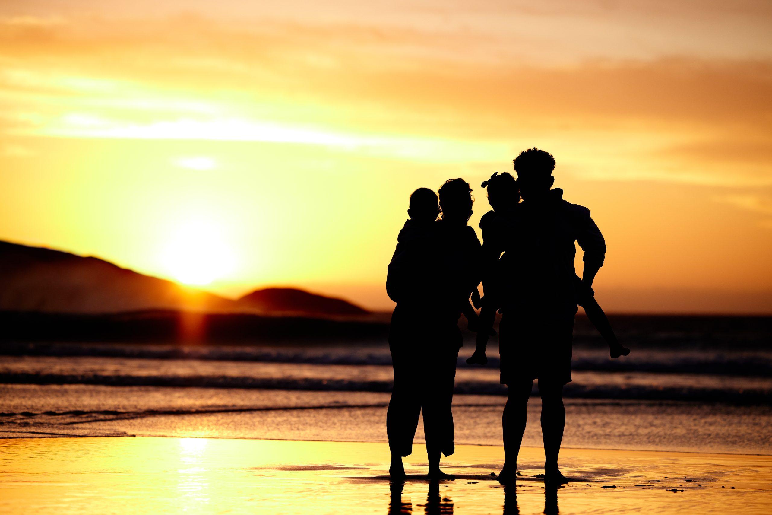 family of 4 enjoying a sunset at the beach